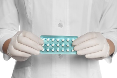 Doctor holding blister of oral contraception pills on white background, closeup