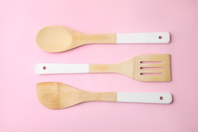 Photo of Wooden kitchen utensils on pink background, flat lay