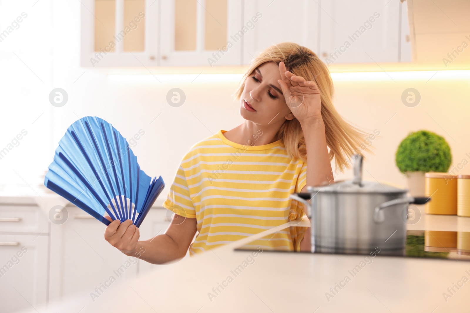 Photo of Woman with hand fan suffering from heat at home. Summer season