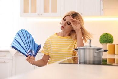 Woman with hand fan suffering from heat at home. Summer season