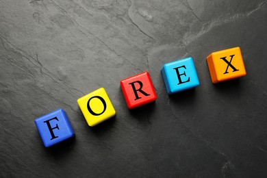 Photo of Word Forex made with colorful cubes on black table, flat lay