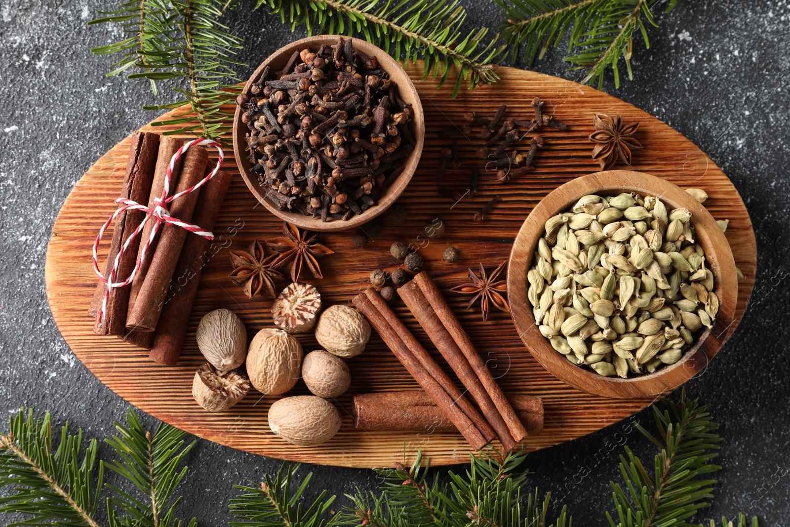 Photo of Different spices and fir branches on dark gray textured table, flat lay