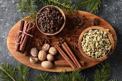 Photo of Different spices and fir branches on dark gray textured table, flat lay