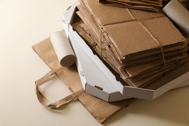 Photo of Stack of different waste paper on beige background, closeup
