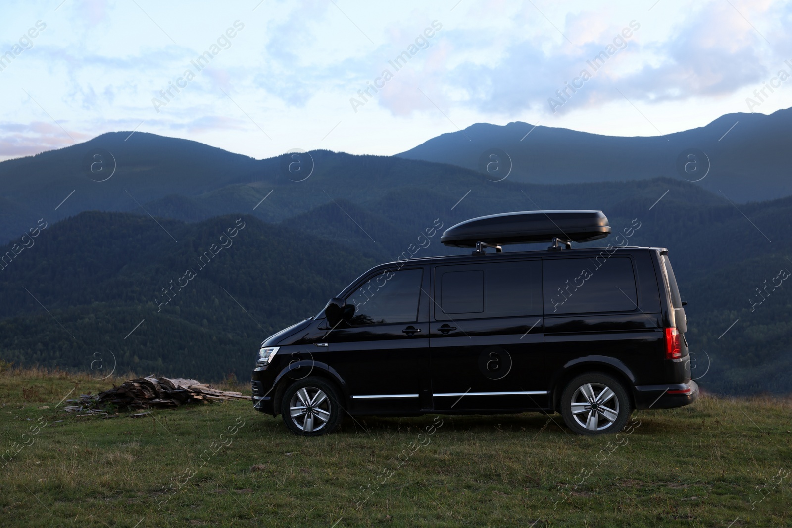 Photo of Black van parked in clearing among mountains