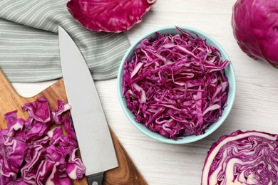Photo of Tasty fresh shredded red cabbage in bowl on white wooden table, flat lay