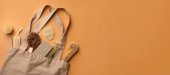 Photo of Bag with eco friendly products on orange background, flat lay. Conscious consumption