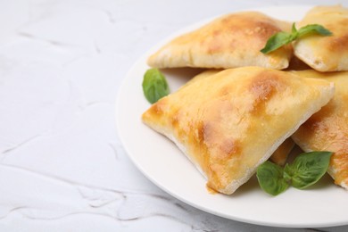 Photo of Delicious samosas and basil on white textured table, closeup. Space for text