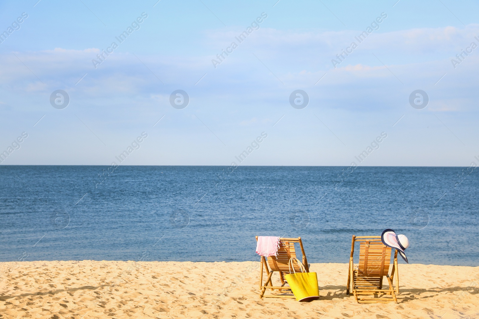 Photo of Empty wooden sunbeds and beach accessories on sandy shore