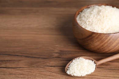 Photo of Uncooked rice on wooden table. Space for text