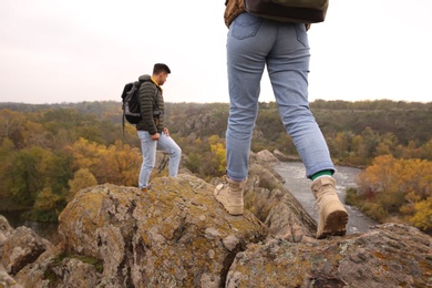 Photo of Couple of hikers with backpacks climbing up mountains, closeup