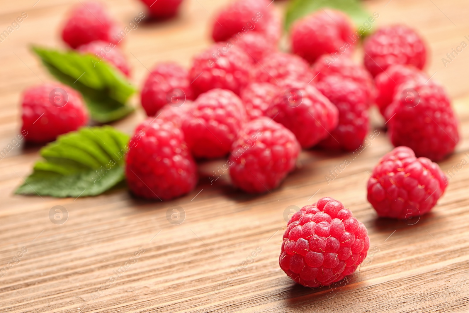 Photo of Ripe aromatic raspberries on wooden table