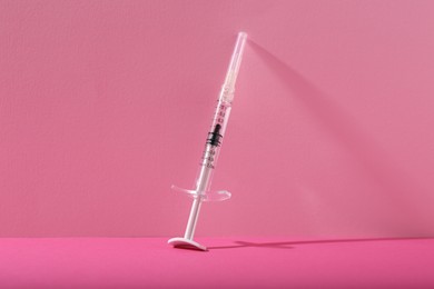 Photo of Cosmetology. One medical syringe on pink background