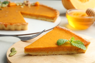 Photo of Piece of delicious fresh homemade pumpkin pie on light grey table, closeup