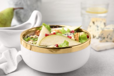 Photo of Delicious pear salad in bowl on light table, closeup