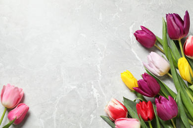 Beautiful spring tulips on grey marble table, flat lay. Space for text