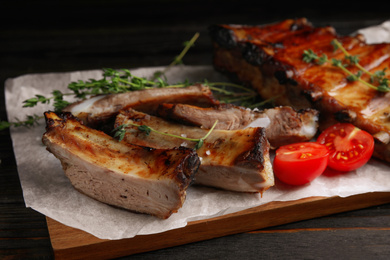 Photo of Tasty grilled ribs on black wooden table, closeup