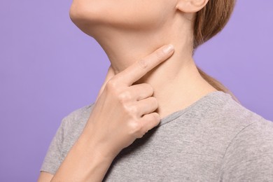 Photo of Woman suffering from sore throat on violet background, closeup