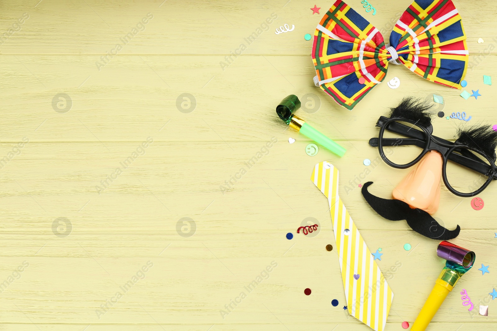 Photo of Flat lay composition with clown's items on light wooden table, space for text