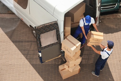 Male movers unloading boxes from van outdoors, above view