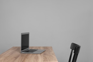 Photo of New modern laptop on empty wooden table indoors, space for text