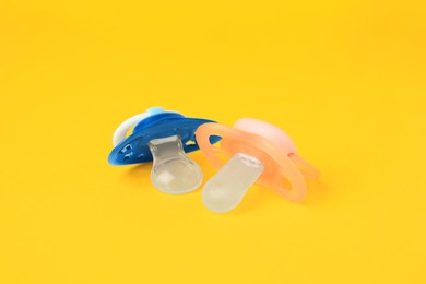 Photo of Colorful baby pacifiers on bright orange background