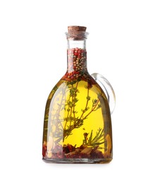 Photo of Glass jug of cooking oil with spices and herbs isolated on white