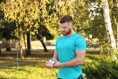 Photo of Young man checking pulse after workout in park