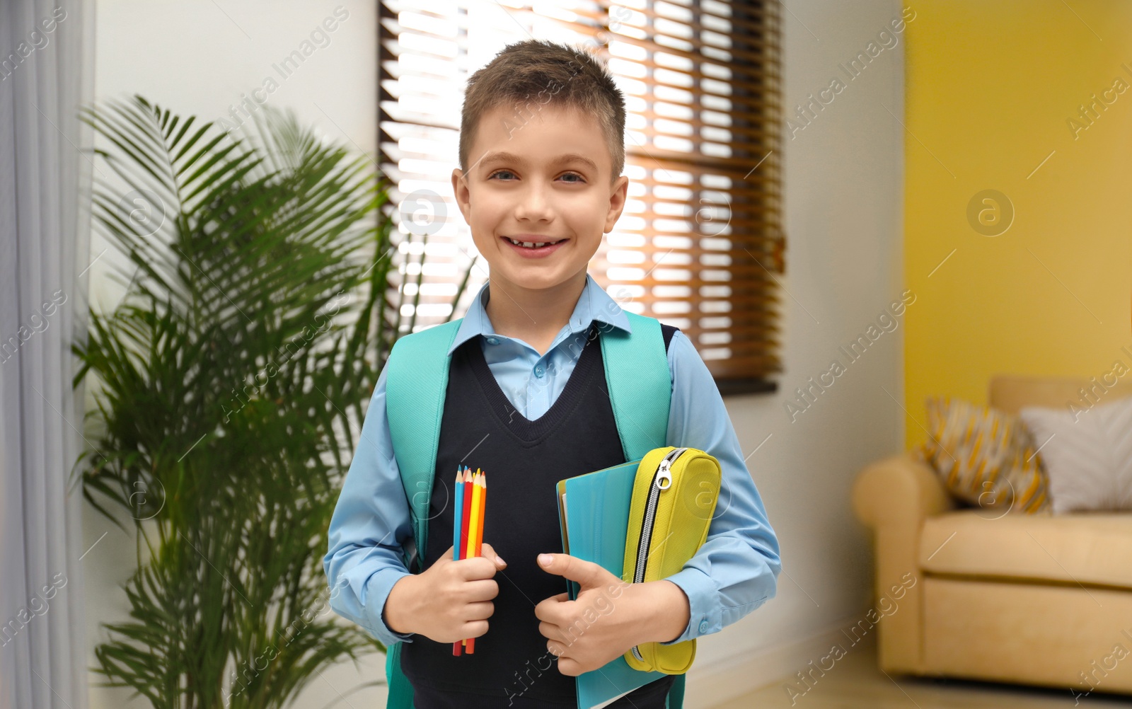Photo of Little boy in uniform with school stationery at home