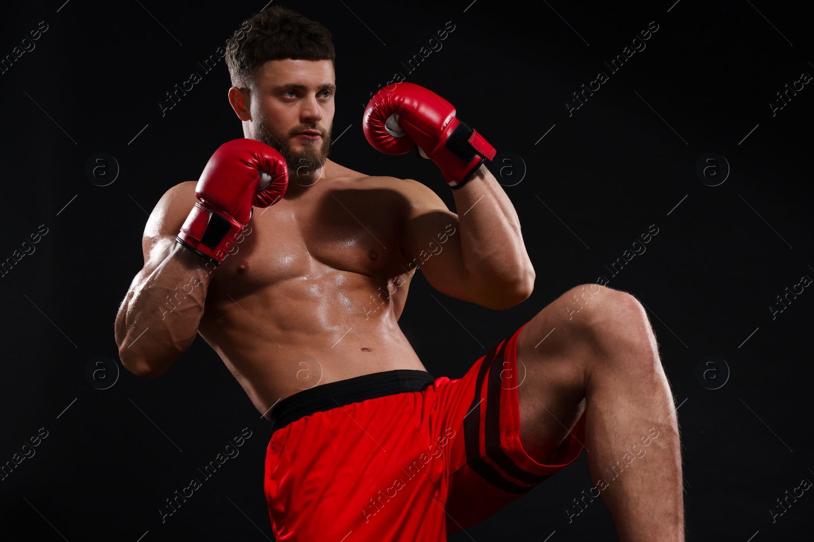 Photo of Man in boxing gloves fighting on black background