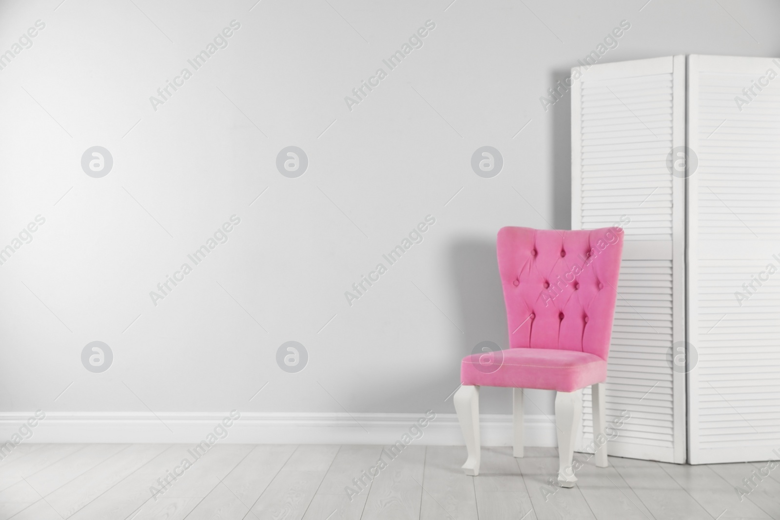 Photo of Stylish pink chair and folding screen near white wall. Space for text