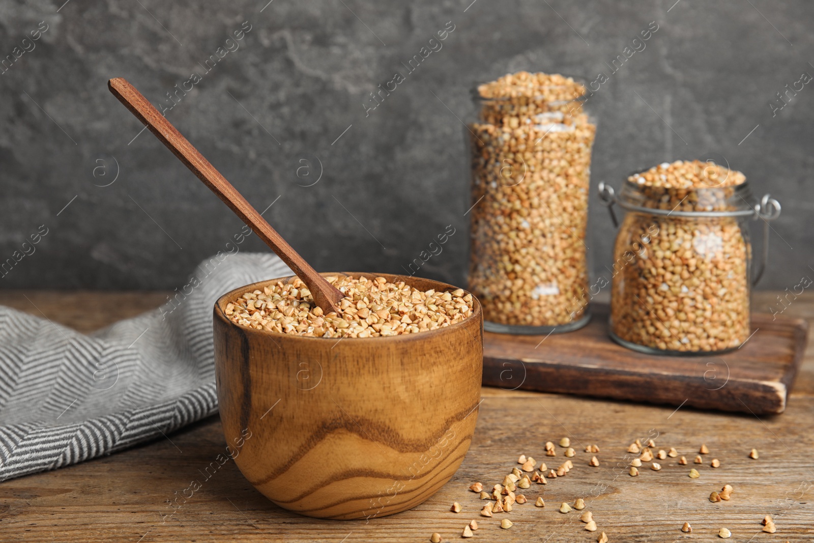 Photo of Uncooked green buckwheat grains in bowl on wooden table