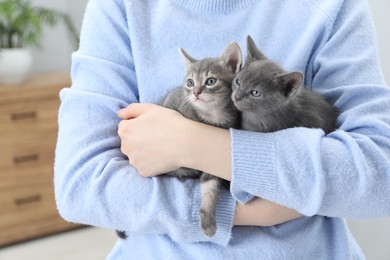 Photo of Woman with cute fluffy kittens indoors, closeup