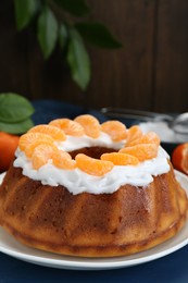 Photo of Homemade yogurt cake with tangerines and cream on blue wooden table