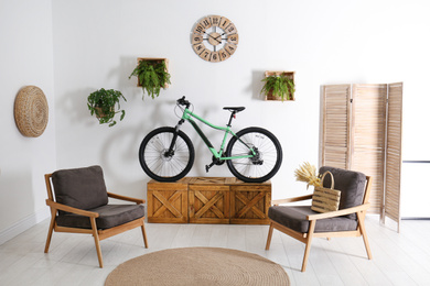 Modern bicycle and comfortable armchairs in stylish living room interior