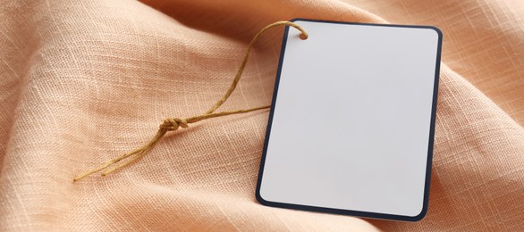 Image of Blank tag on light orange fabric, closeup view with space for text. Banner design