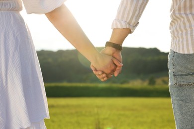 Romantic date. Couple holding hands outdoors, closeup