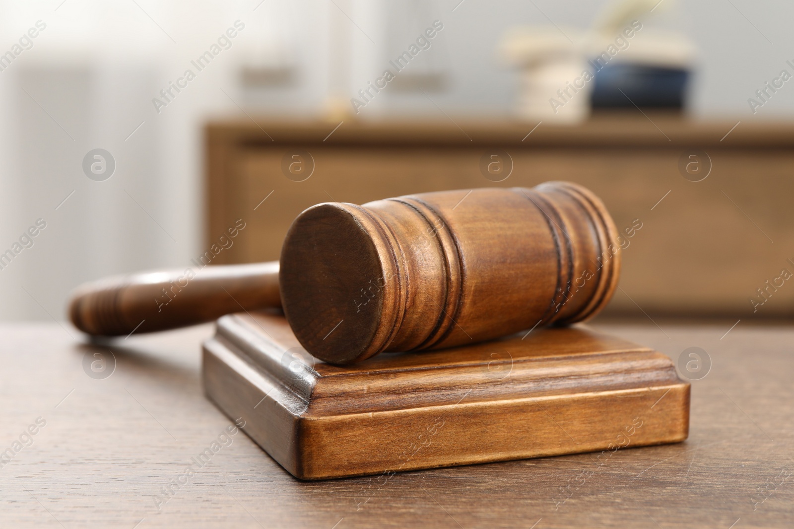 Photo of Wooden gavel and sound block on table indoors, closeup