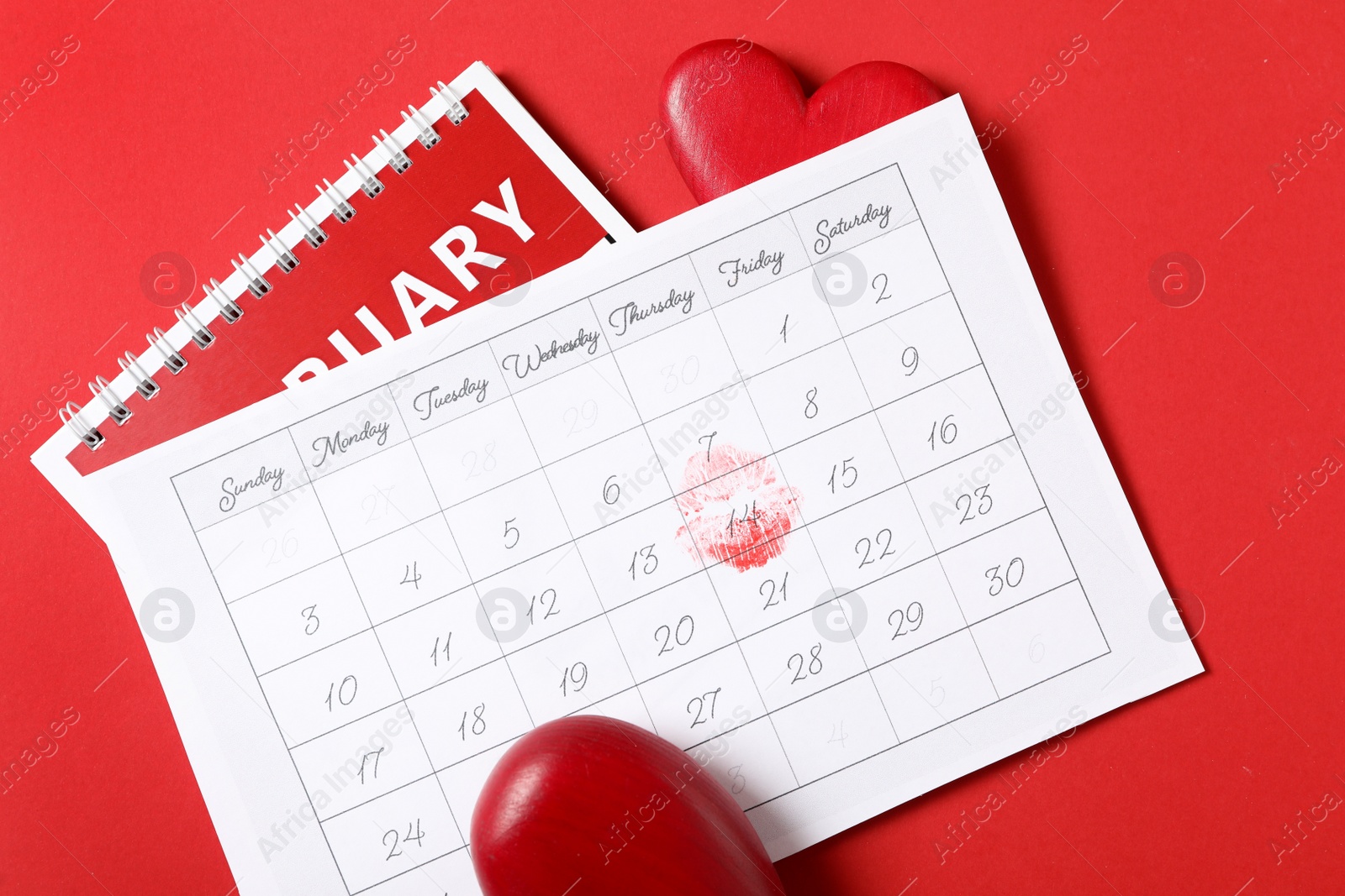 Photo of Calendar with marked Valentine's Day and wooden hearts on red background, flat lay