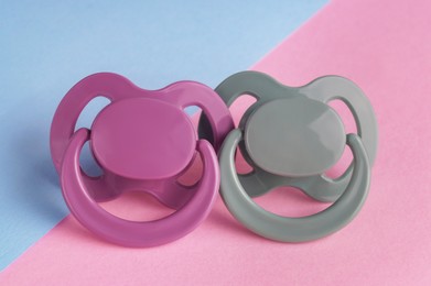 Photo of New baby pacifiers on color background, closeup