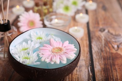 Photo of Spa composition. Bowl with water and beautiful flowers on wooden table, closeup. Space for text