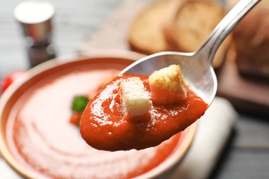 Spoon with fresh homemade tomato soup on blurred background, closeup