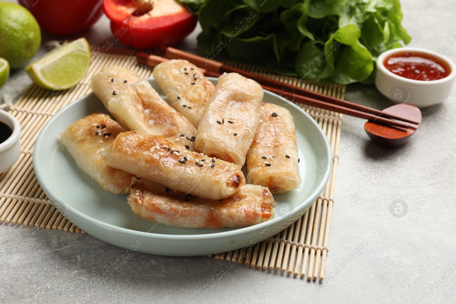 Photo of Tasty fried spring rolls served on gray table, closeup