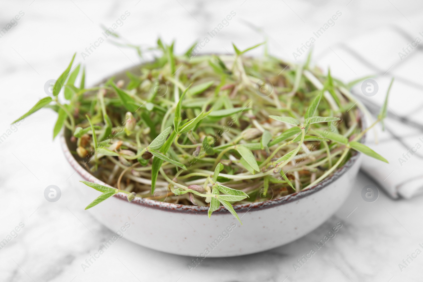 Photo of Mung bean sprouts in bowl on white marble table, closeup