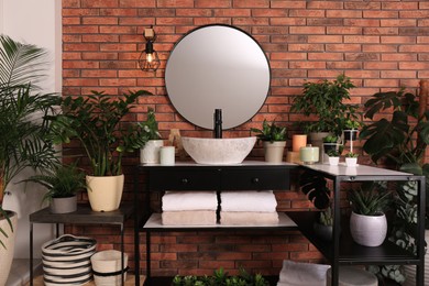 Photo of Stylish bathroom interior with modern sink, furniture and beautiful green houseplants
