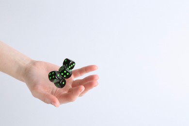 Photo of Woman throwing game dices on white background, closeup. Space for text