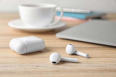 Wireless earphones and charging case on wooden table