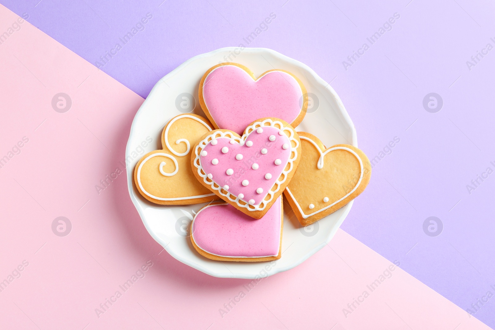 Photo of Plate with decorated heart shaped cookies on color background, top view