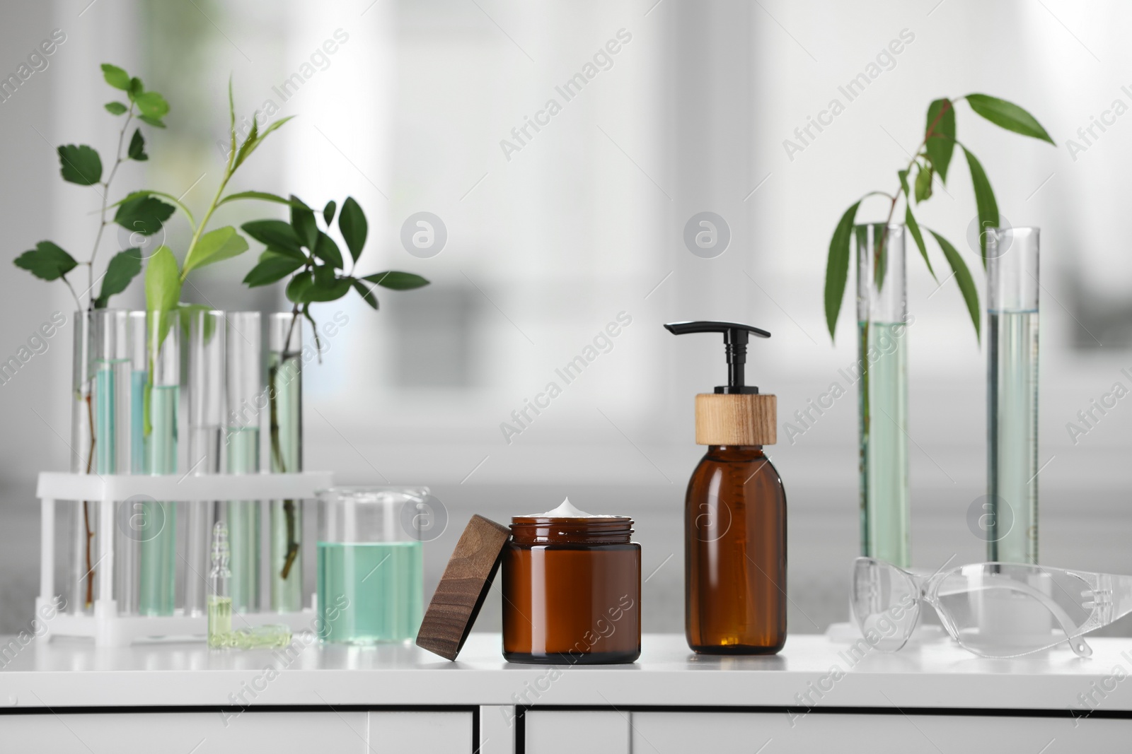 Photo of Bottle, jar and glass tubes with leaves on white lab drawer indoors