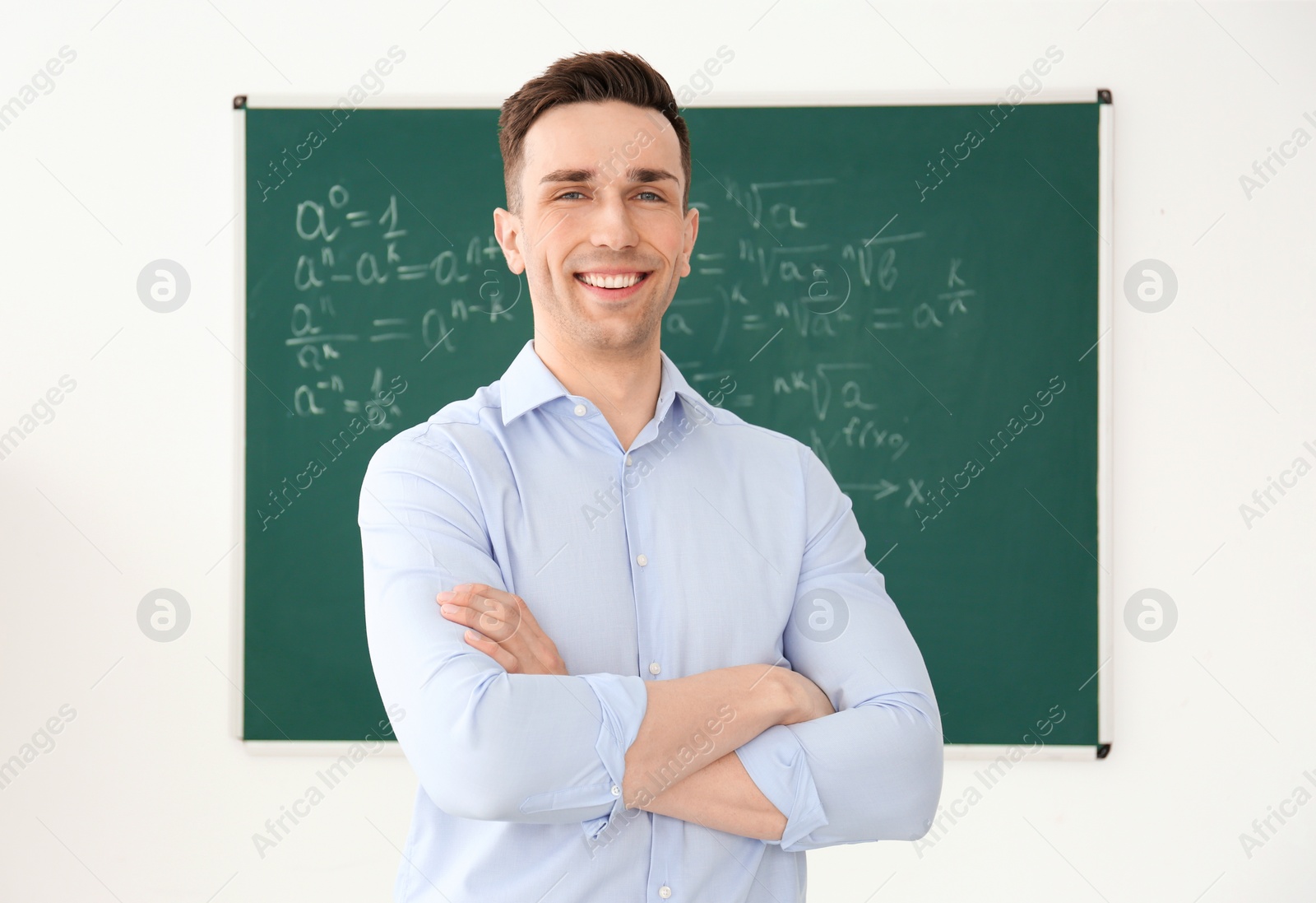 Photo of Young male teacher standing in classroom